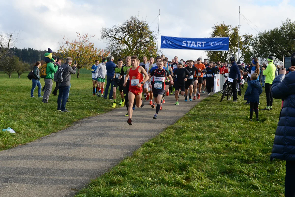 Weil an einer Stelle ein Absperrband heruntergerissen war, rannten rund 60 Teilnehmerinnen und Teilnehmer des Panoramalaufs in die falsche Richtung. Statt 5,7 Kilometer legten sie etwa 9 Kilometer zurück. (Archiv) Eine Gruppe rennt auf einem Weg. Im Hintergrund ist in der Höhe ein Banner mit der Aufschrift Start zu sehen.